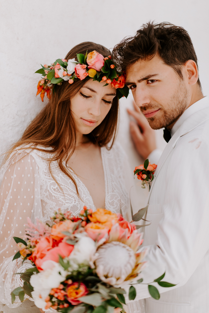 A lovely couple in elegant wedding attire, wearing a white dress and a charming flower crown, mykonos wedding