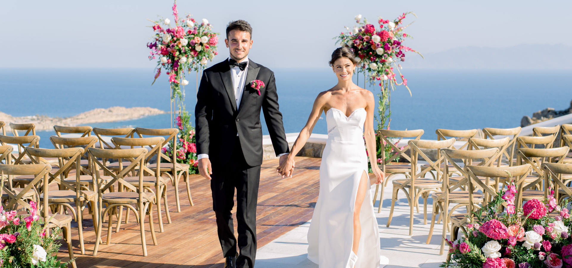 A newlywed couple walks down the aisle, hand in hand, surrounded by their loved ones on their wedding day.