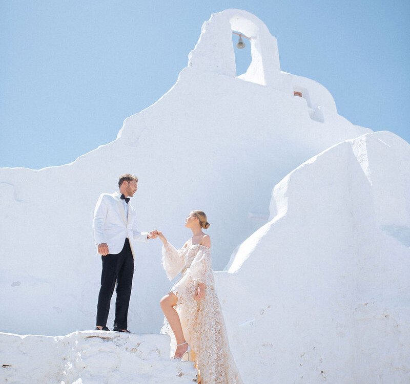 Elegant wedding couple at white chapel in Mykonos, Greek island setting